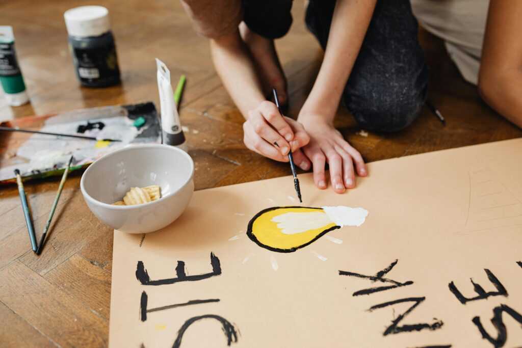 A student is painting a lightbulb for a school art project, focusing on creativity and expression.