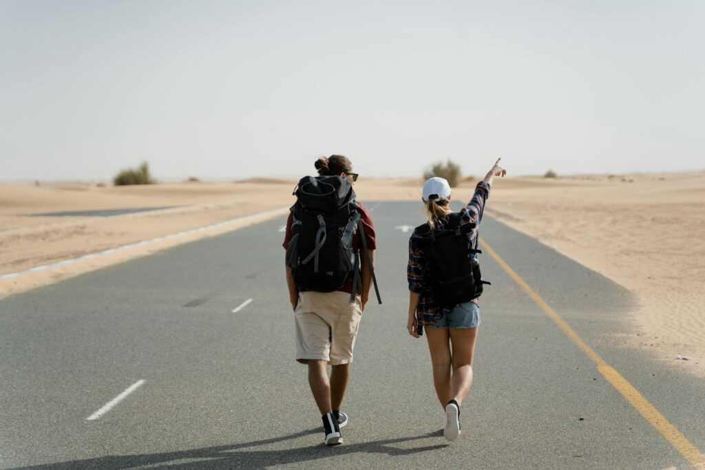 Adventure in the desert with two people walking down a long road.