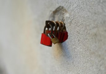 A series of red padlocks attached to a stone wall, symbolizing security and love.